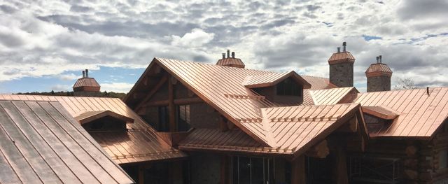 Cuivre patiné sur chalet en bois rond avec multiples pignons
